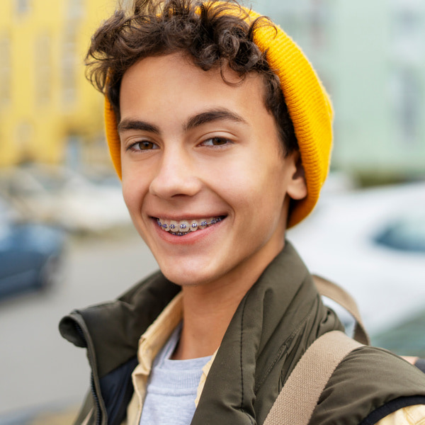 A boy in a yellow hat is joyfully smiling on the street