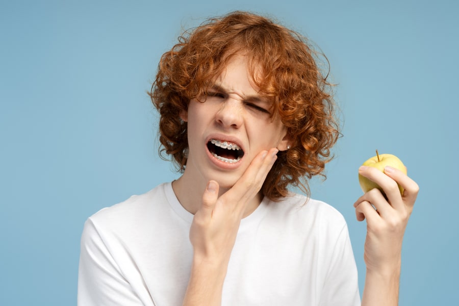 A boy is experiencing discomfort and holding an apple in his hand
