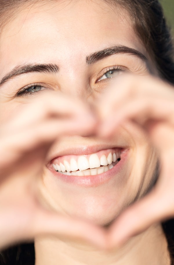 A woman sowing heart with her hands and smiling