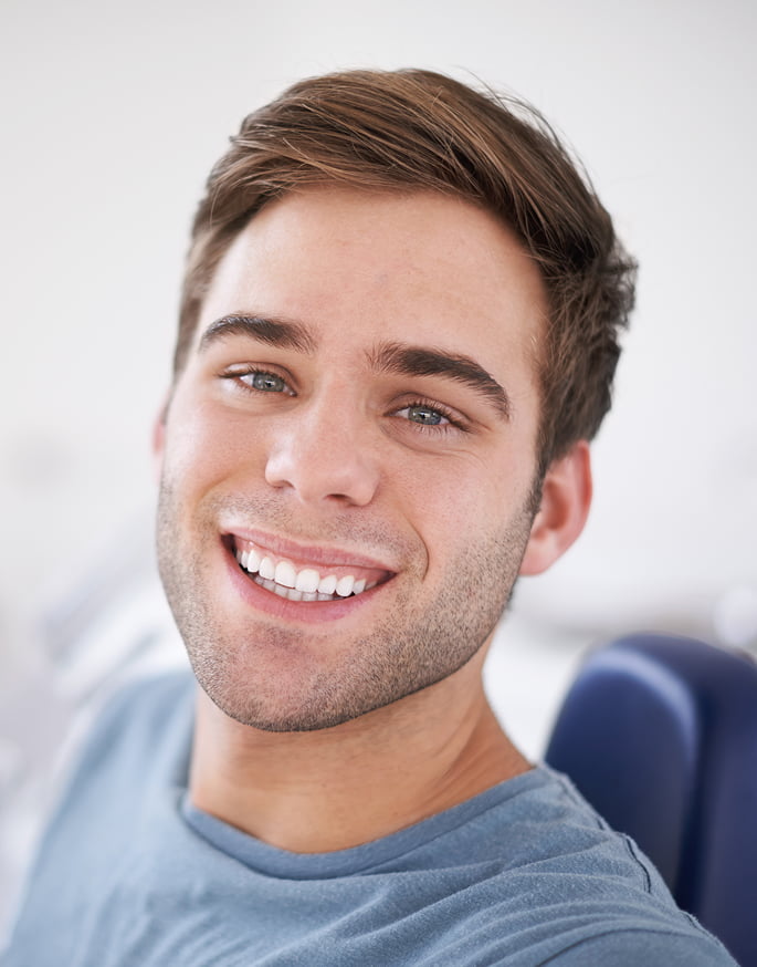 A smiling man sits comfortably in a dental chair, appearing relaxed during his dental appointment
