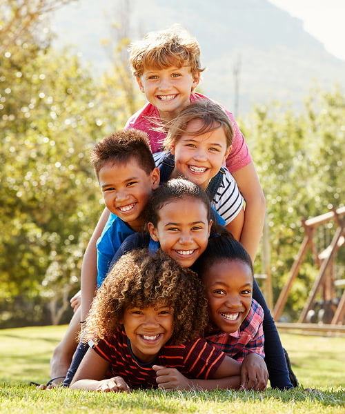 A group of children sitting on the grass, enjoying a sunny day together in a playful outdoor setting