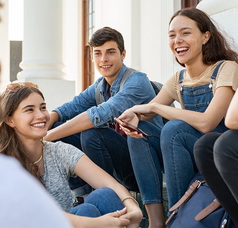 A diverse group of young people sitting on the steps of a building, engaged in conversation and enjoying each other's company